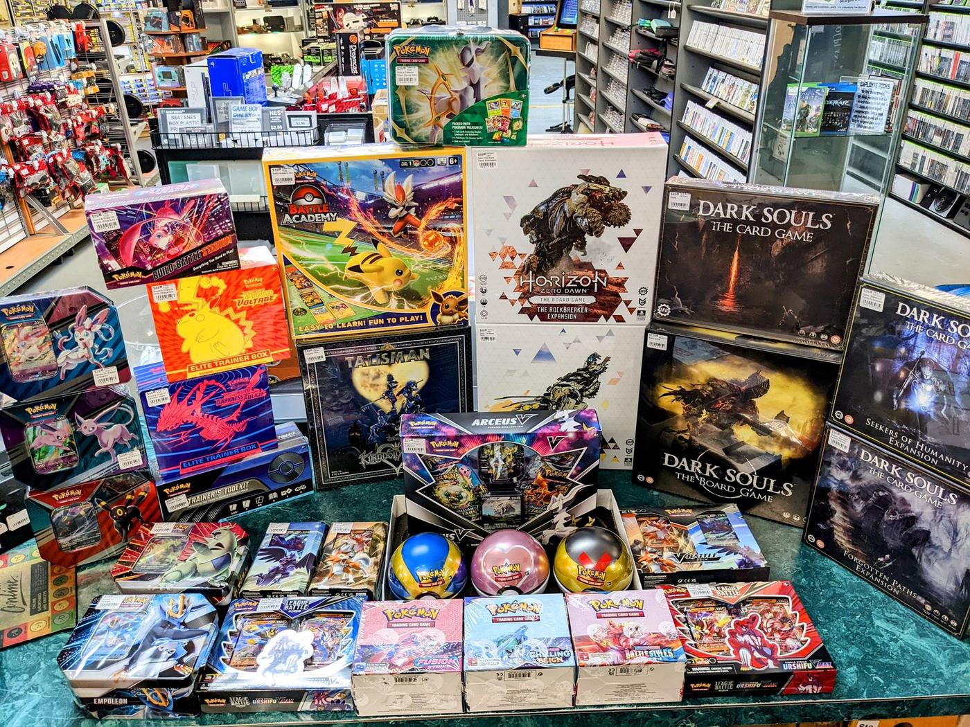 Dark Souls board games, Pokémon boxes and gaming merch on a table